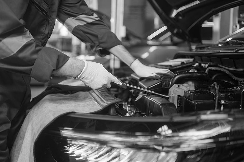 Removing tires from car. Close-up of young man using pneumatic wrench while working with car tire in workshop