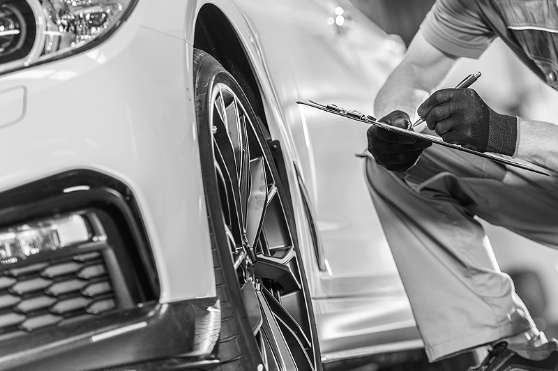 Removing tires from car. Close-up of young man using pneumatic wrench while working with car tire in workshop